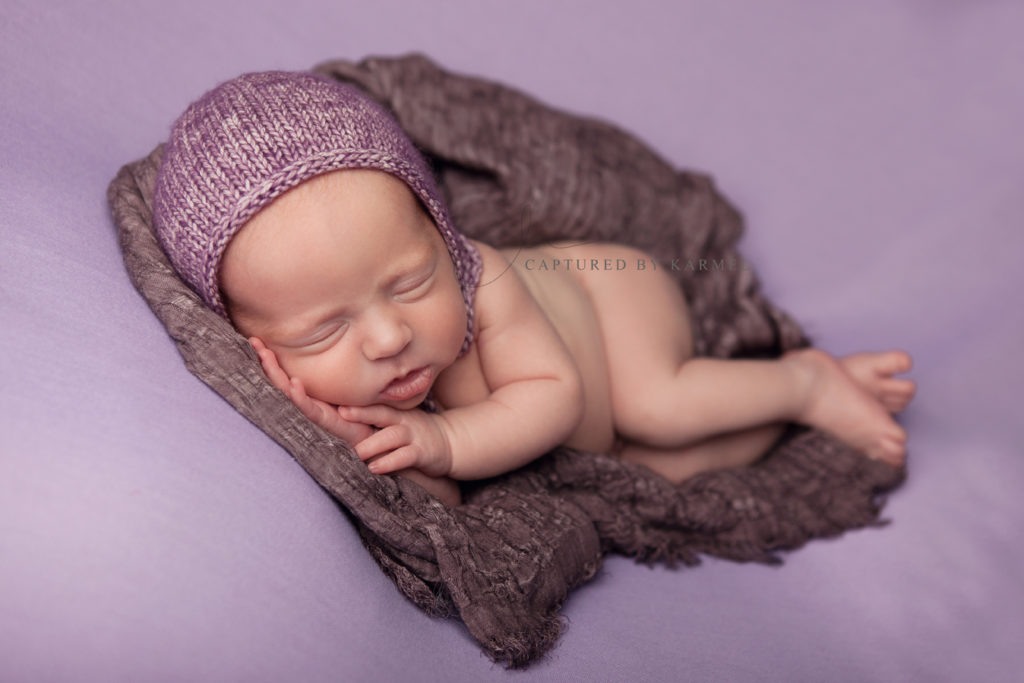 newborn sleeping on purple backdrop