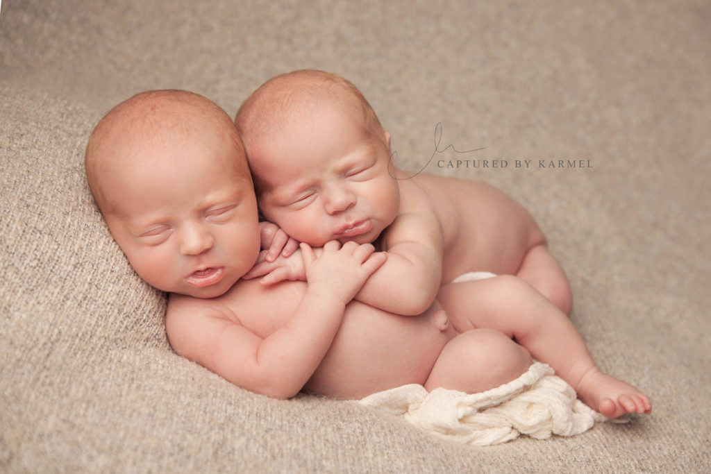 identical twins sleeping on cream backdrop